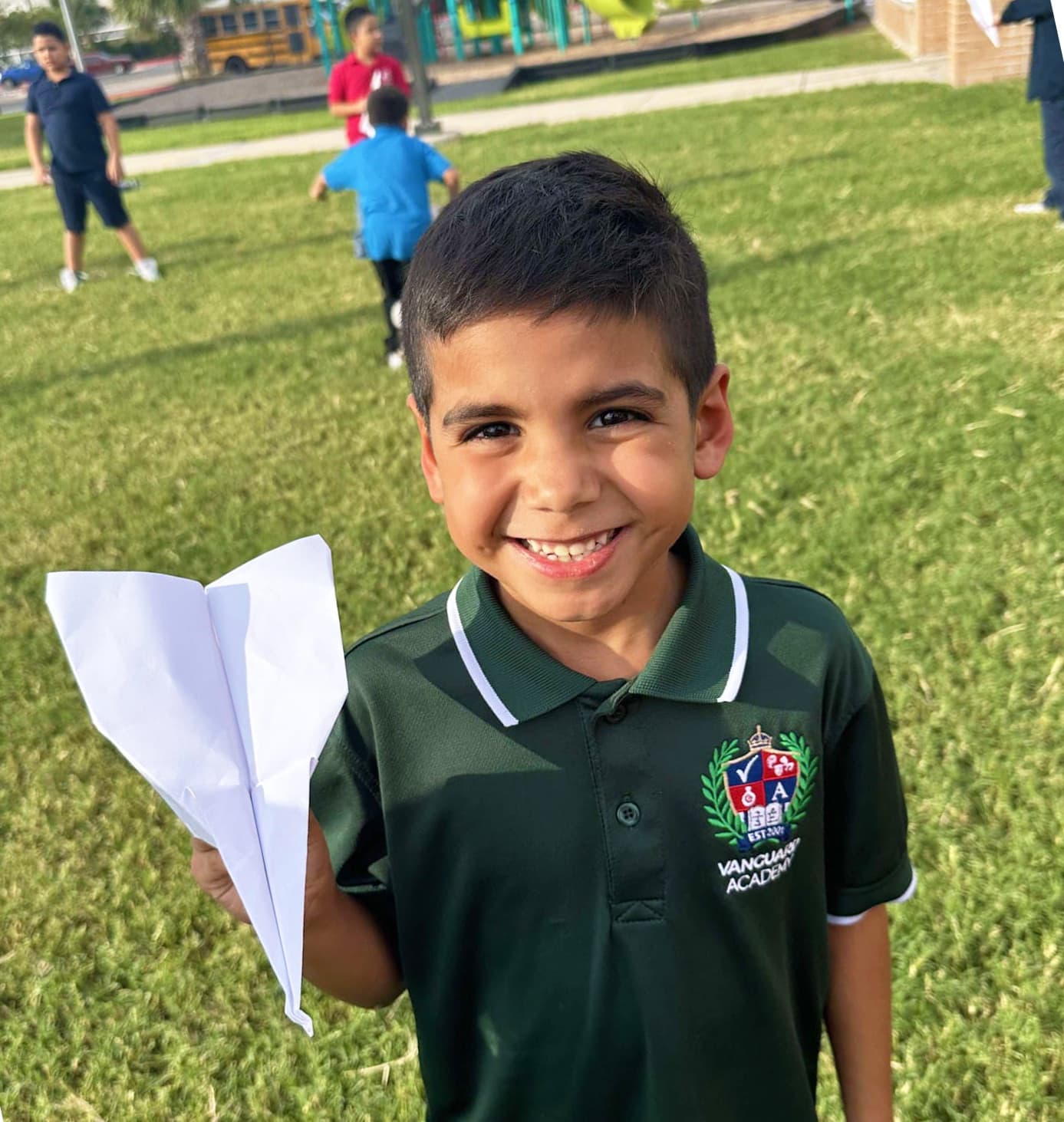 A smiling Club member holding a paper airplane during outdoor play
